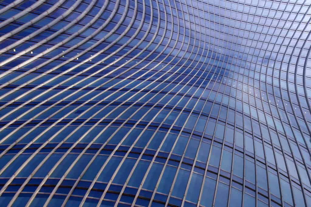 Close-up of a modern building facade with curved blue glass panels and silver structural lines.