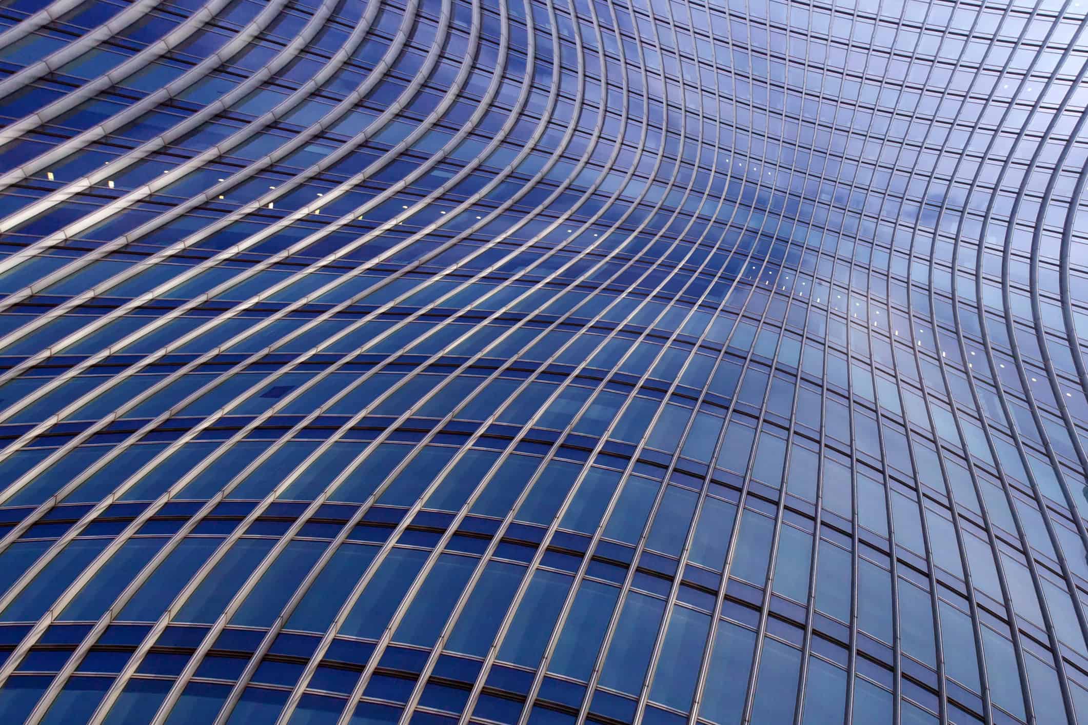 Close-up of a modern building facade with curved blue glass panels and silver structural lines.