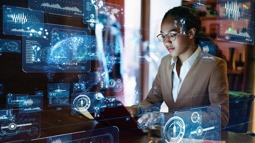 A woman in glasses and a blazer interacts with multiple glowing blue holographic data displays and graphs in a futuristic setting.