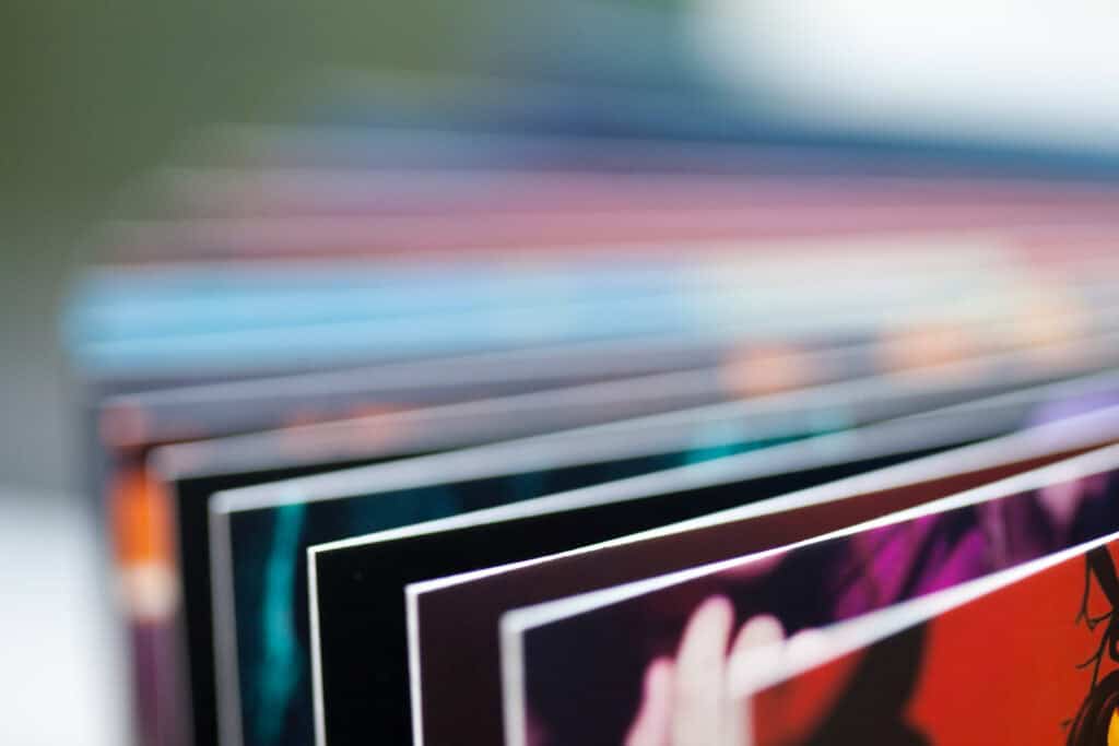 Close-up of fanned-out photo album pages with colorful images and white borders, showing a red page in the foreground.