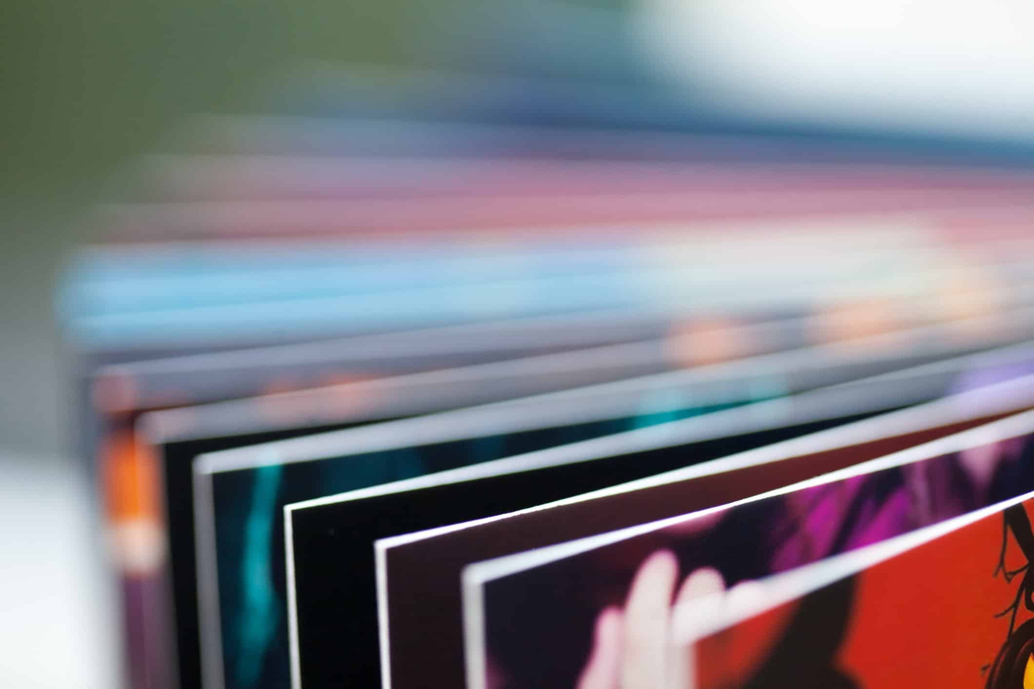Close-up of fanned-out photo album pages with colorful images and white borders, showing a red page in the foreground.