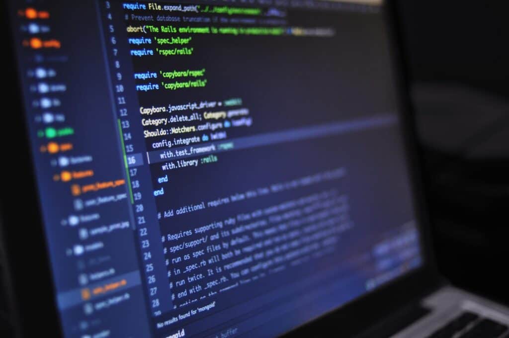 Close-up of a laptop screen displaying Ruby on Rails code in a dark-themed editor with syntax highlighting.