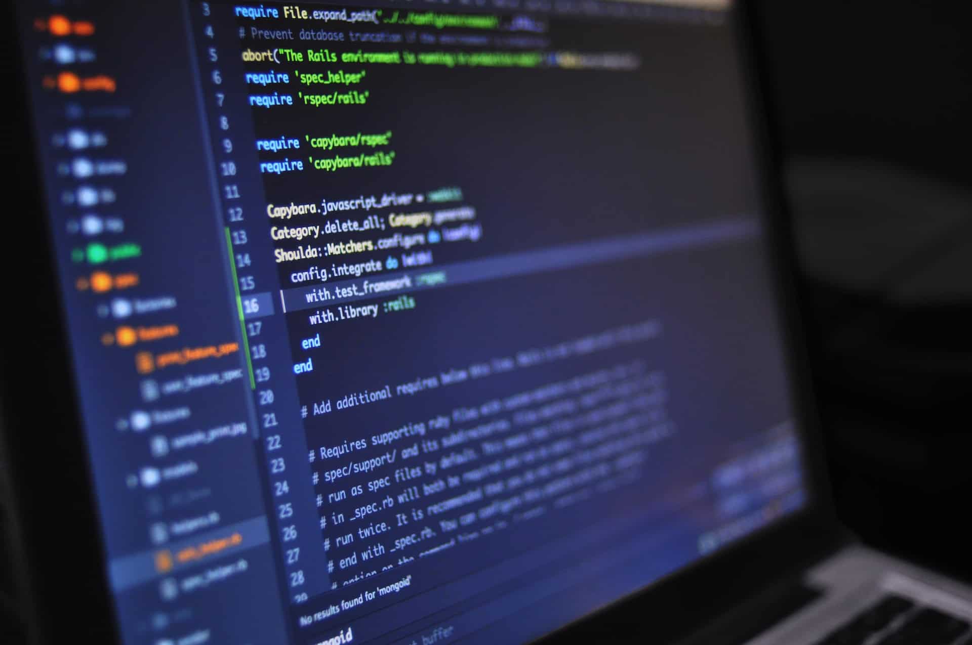 Close-up of a laptop screen displaying Ruby on Rails code in a dark-themed editor with syntax highlighting.