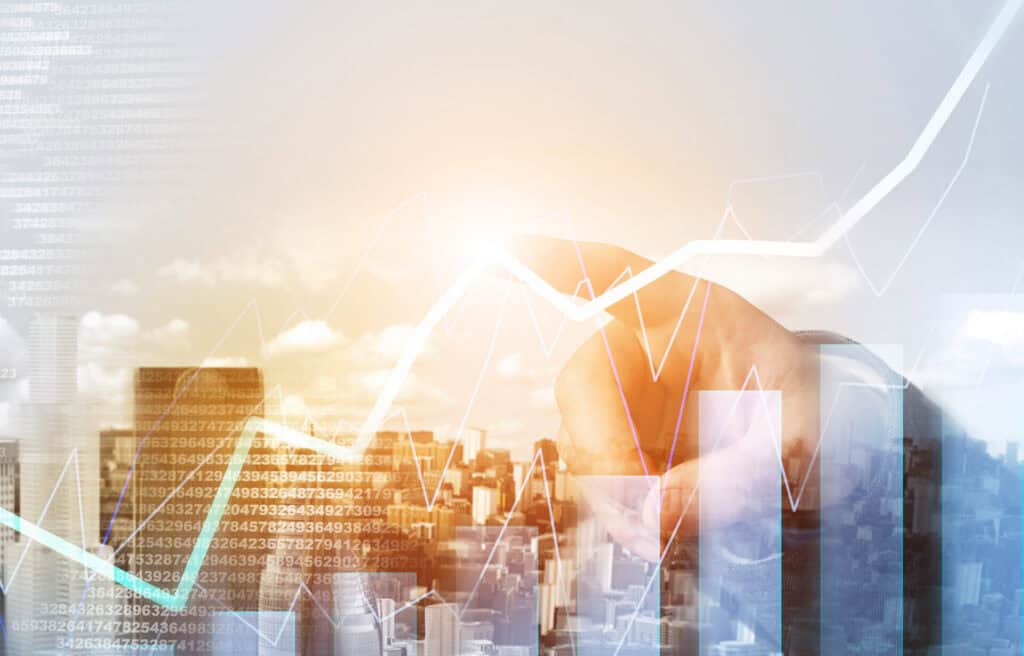 Composite image of a hand interacting with digital graphs and numerical data, overlaid on a city skyline.