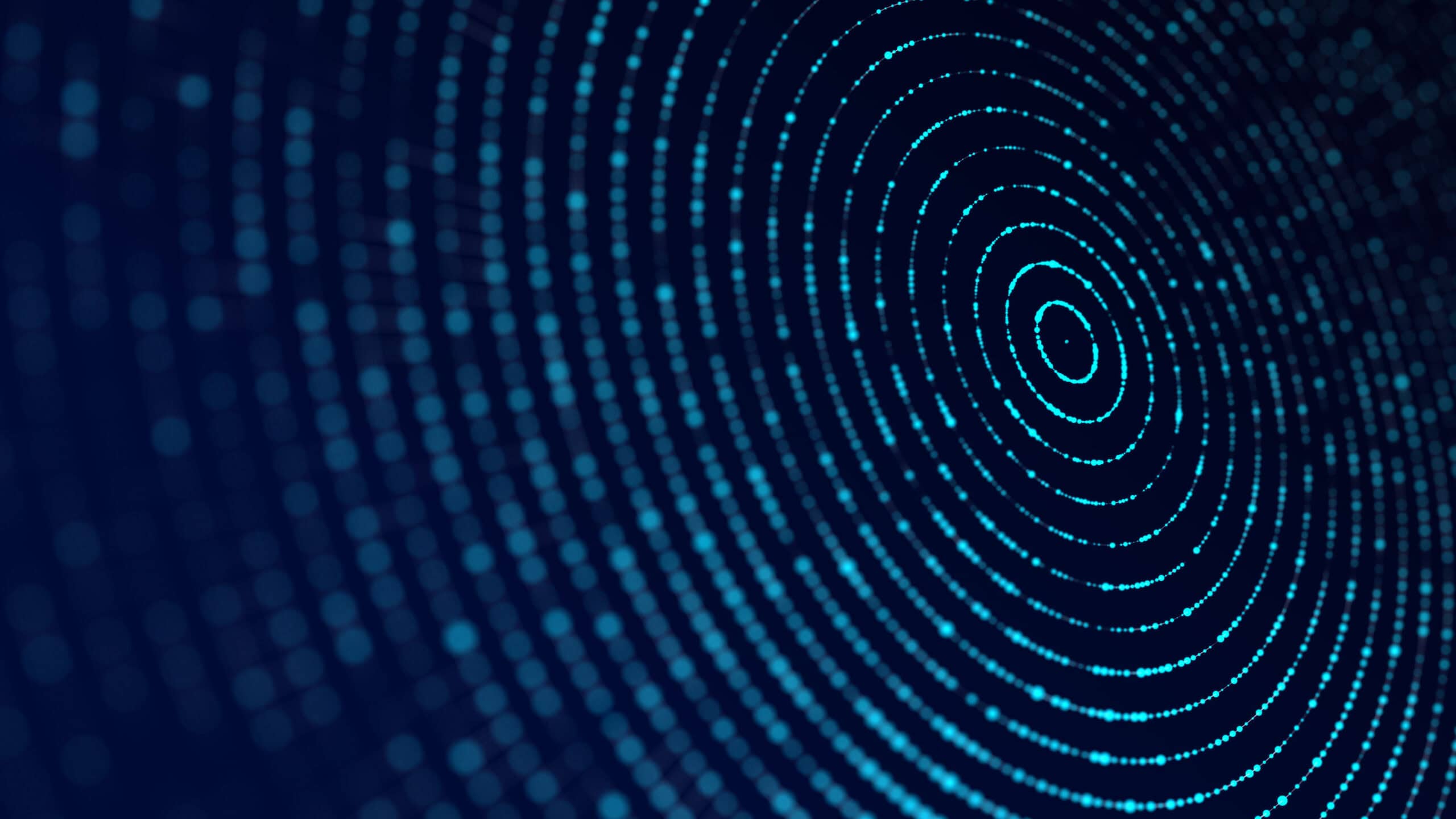 Abstract image of glowing blue dots forming concentric circles on a dark blue background, with some areas blurred.