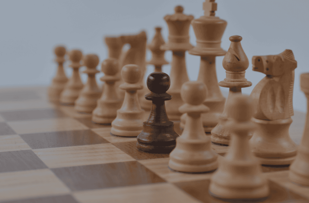 A dark brown chess pawn stands on a chessboard, surrounded by many light-colored chess pieces.