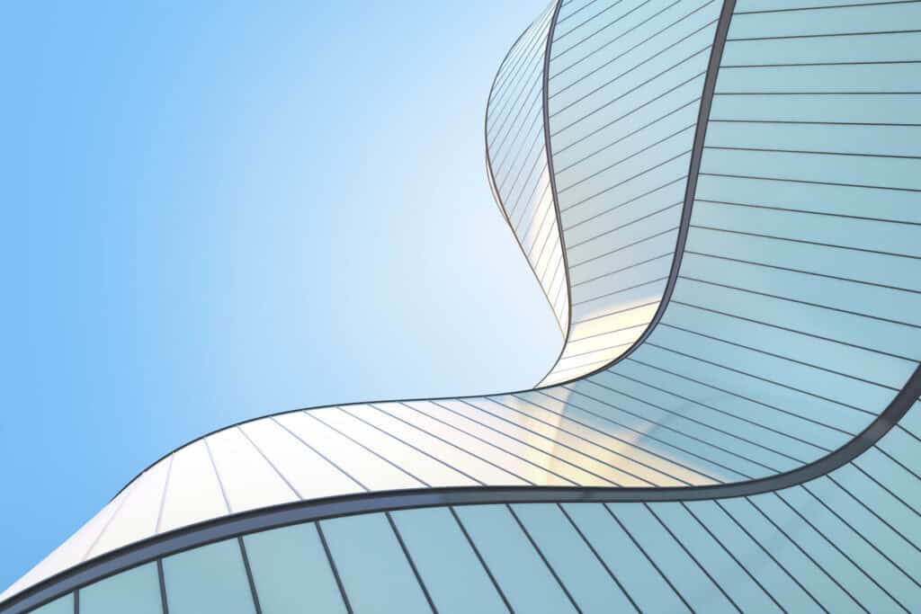 Modern building with a curved glass facade against a bright blue sky.