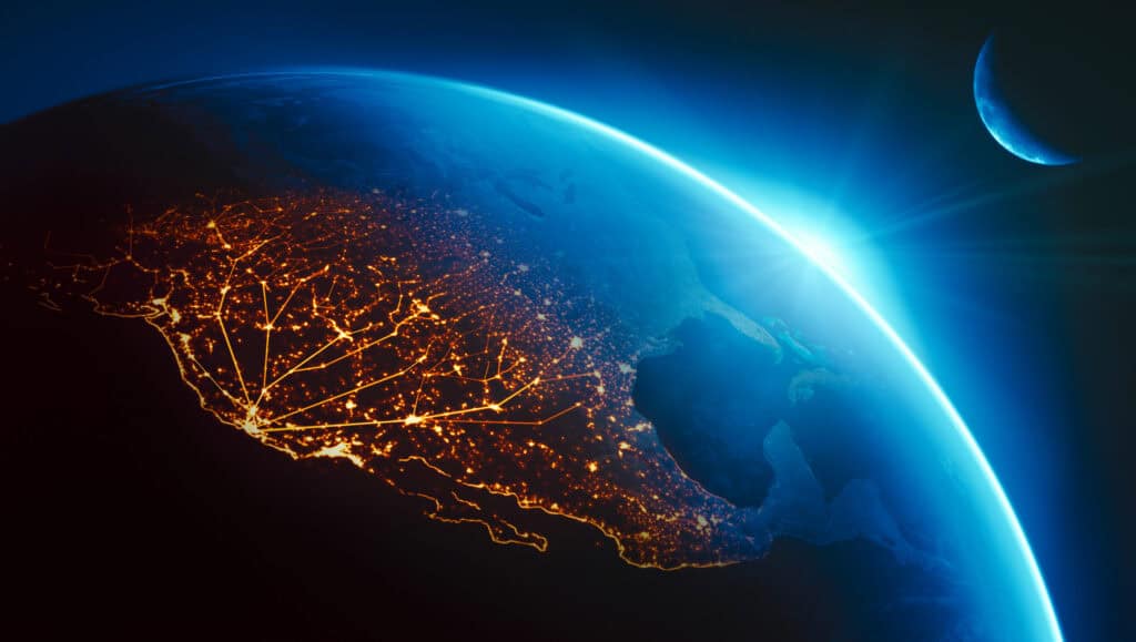 View of Earth from space showing city lights at night, a bright blue sunrise, and a crescent moon.