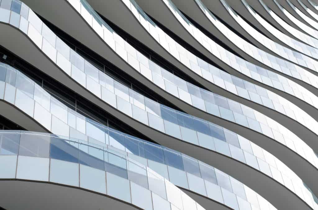 Close-up of a modern building facade with undulating white balconies and glass railings.
