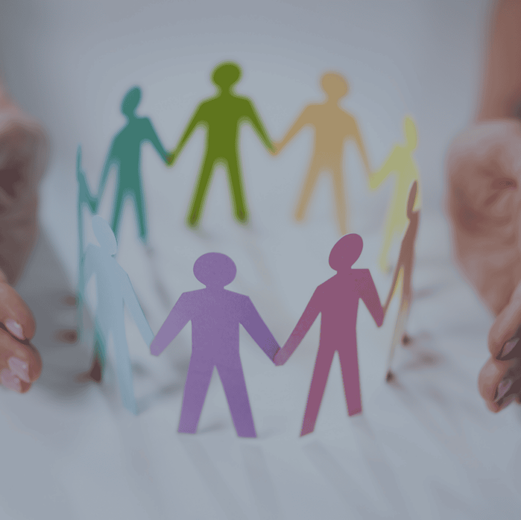 Two hands gently cup a circle of colorful paper cutout figures holding hands on a light surface.