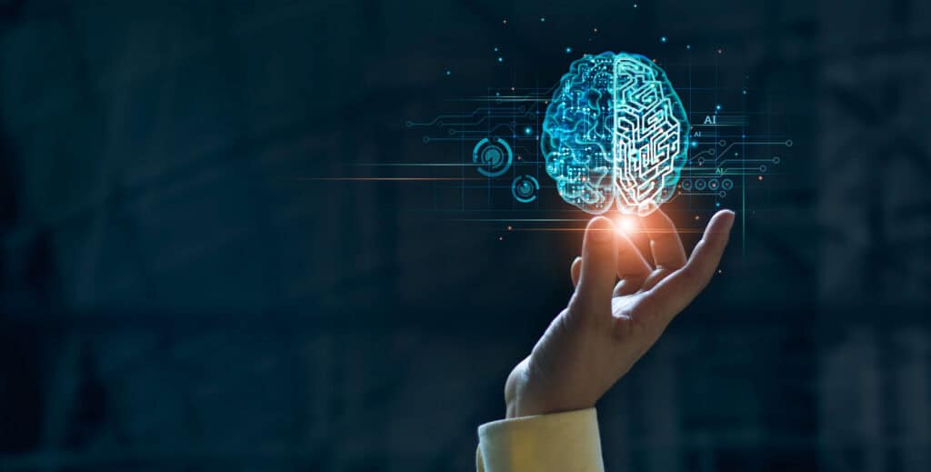 A human hand holds a glowing, translucent digital brain with circuit patterns, symbolizing artificial intelligence and technology.