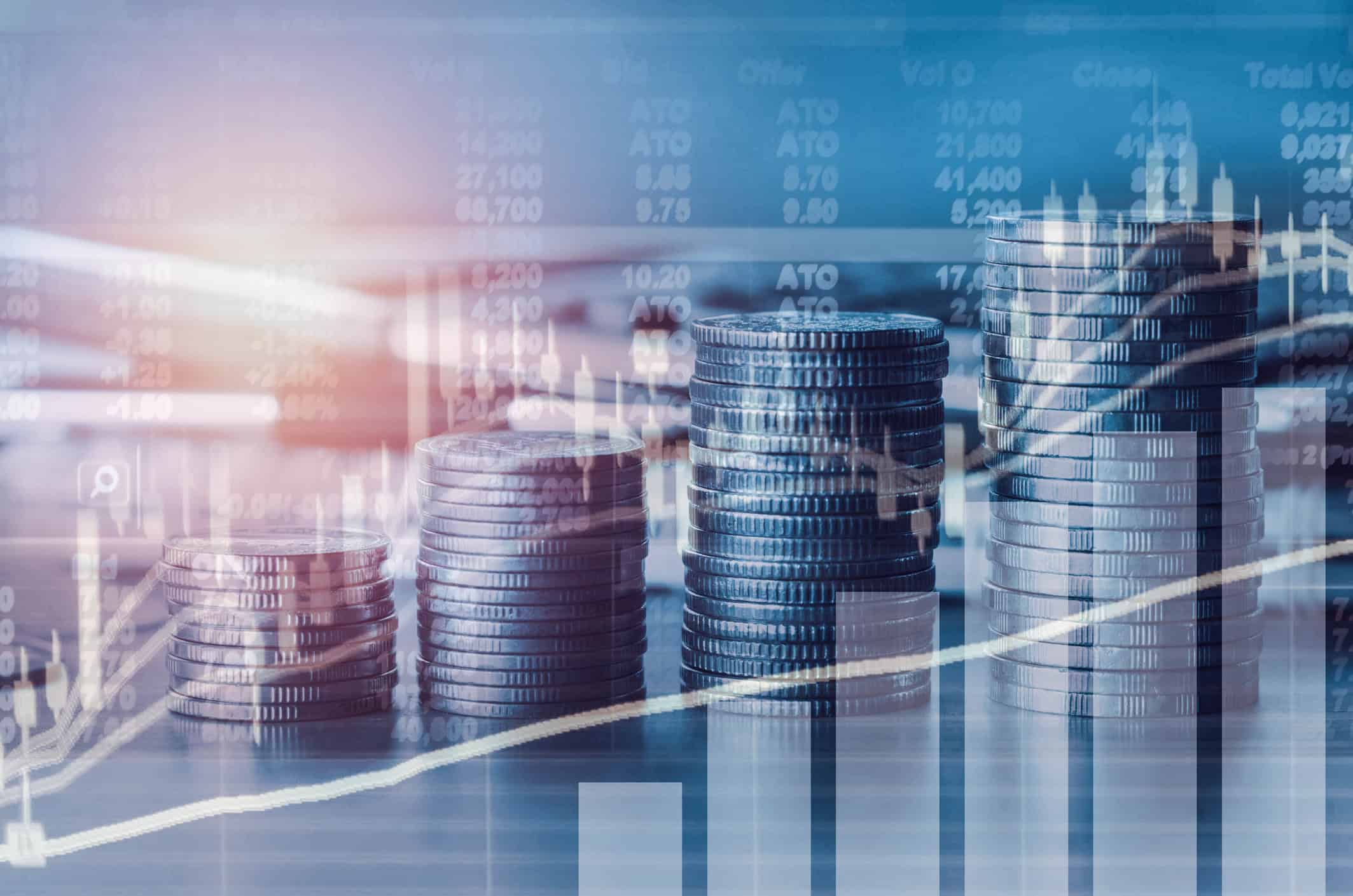 Four stacks of coins of increasing height, overlaid with transparent financial charts and numerical data on a blue and purple background.