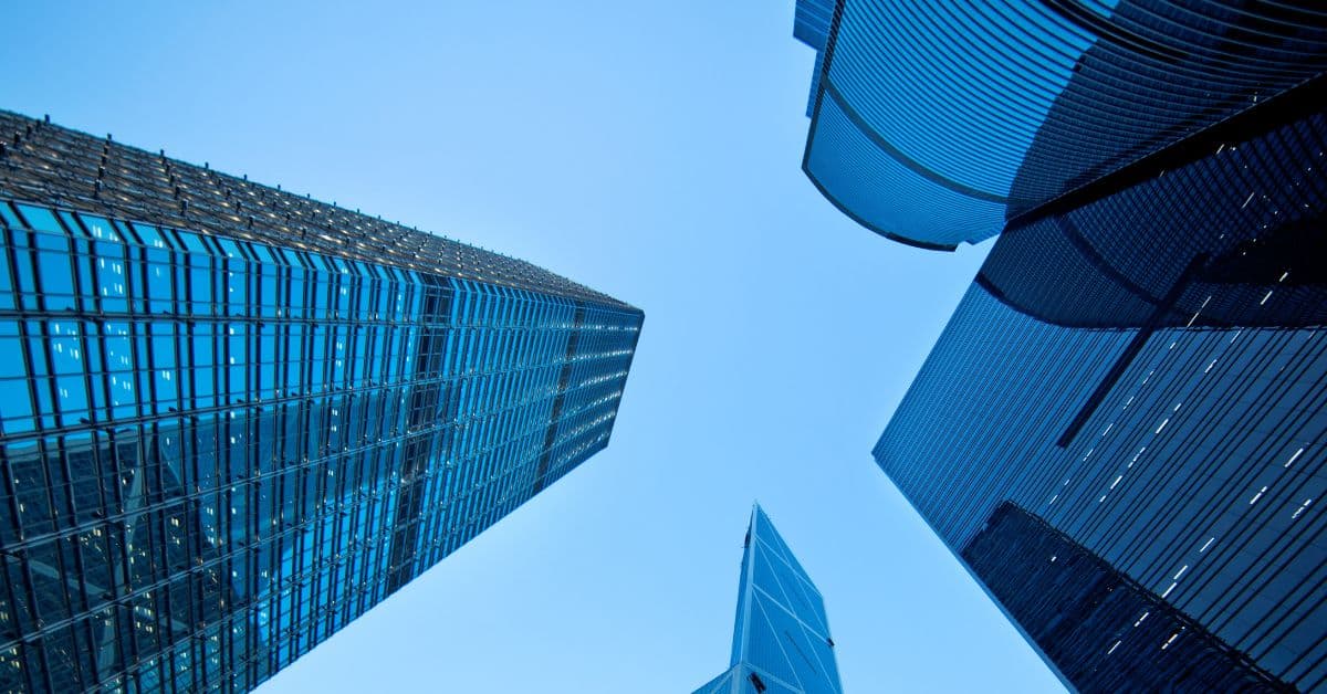 Low-angle view of multiple blue glass skyscrapers against a clear blue sky.