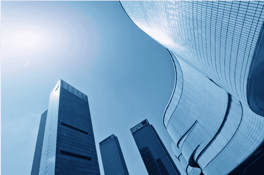 Low-angle view of several modern skyscrapers, including one with a curved facade, against a bright blue sky.