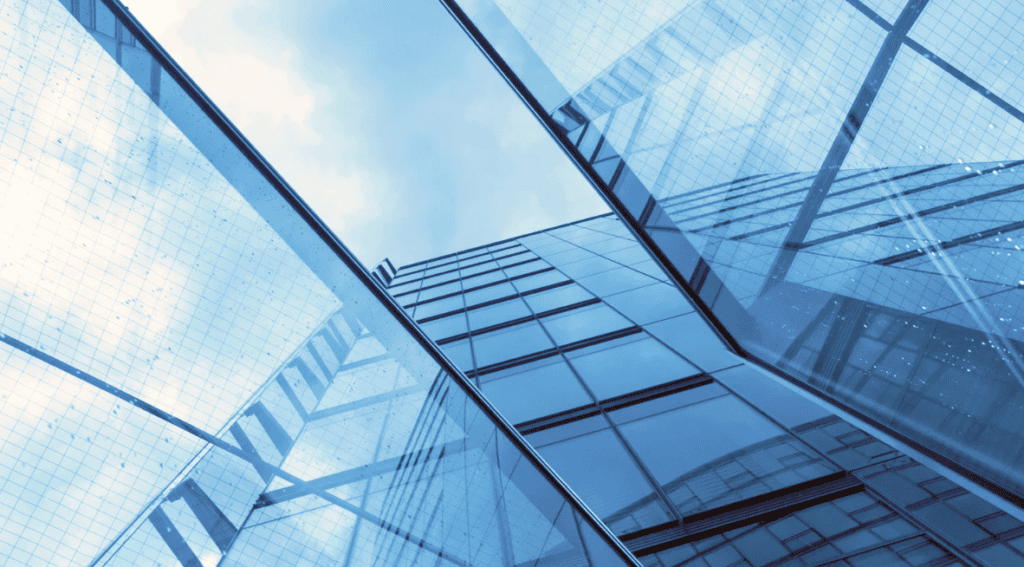 Upward view of a modern building with a blue glass facade reflecting the sky.