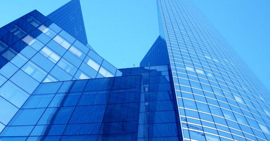 Low-angle view of modern blue glass skyscrapers against a clear blue sky.
