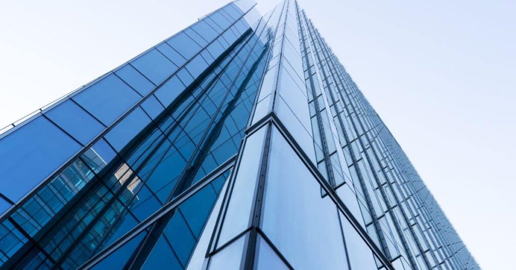 Low-angle view of a modern skyscraper with blue glass panels against a light sky.