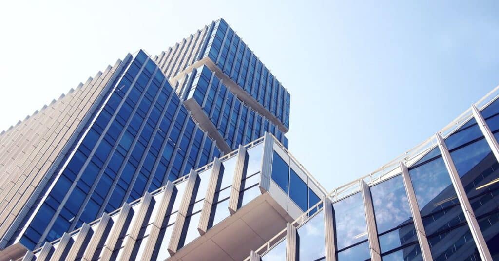 Low-angle view of a modern building with blue glass windows and a stepped design against a clear sky.