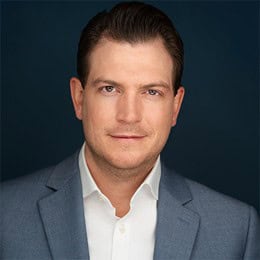 Headshot of a man in a blue suit jacket and white shirt.