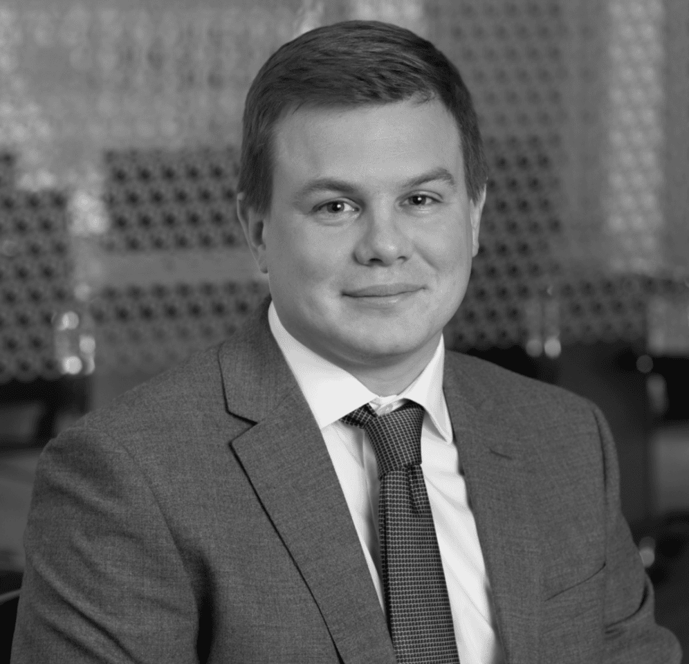 Black and white portrait of a man in a suit and tie, smiling.
