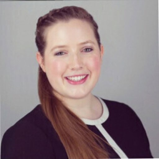 Headshot of a smiling woman with light brown hair in a side ponytail, wearing a black top with white trim.