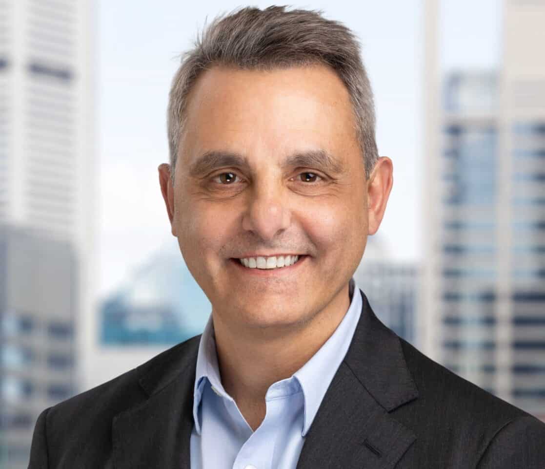 Headshot of a smiling man with gray hair in a suit jacket and blue shirt.