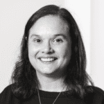 Black and white headshot of a smiling woman with dark hair.