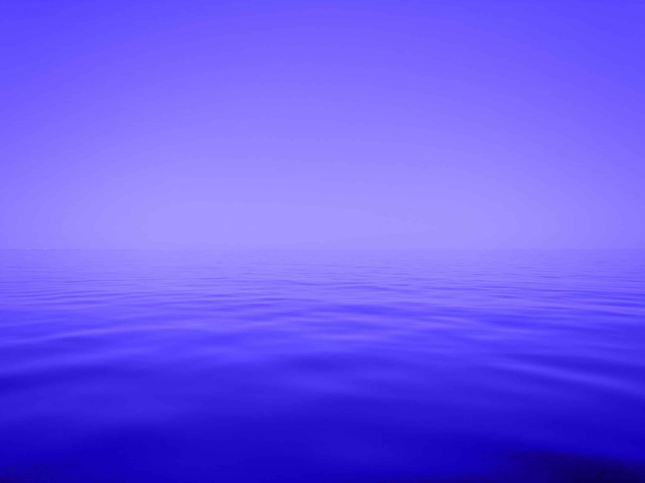 A minimalist image of a light purple sky meeting deep blue, rippling water at the horizon line.