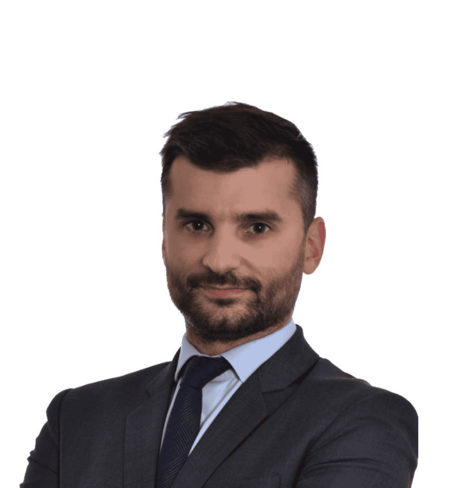 Headshot of a man with dark hair and beard wearing a grey suit and blue tie.