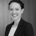 Black and white portrait of a smiling young woman with dark hair pulled back, wearing a blazer.