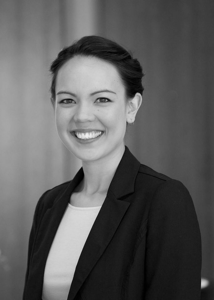 Black and white portrait of a smiling young woman with dark hair pulled back, wearing a blazer.