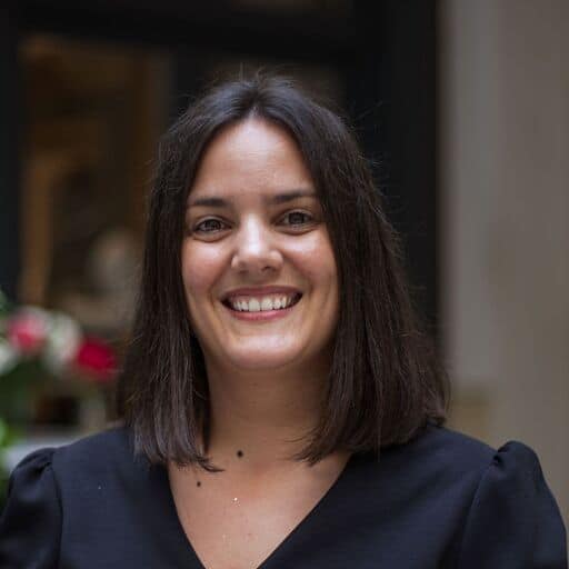 A woman with dark hair smiles directly at the viewer.