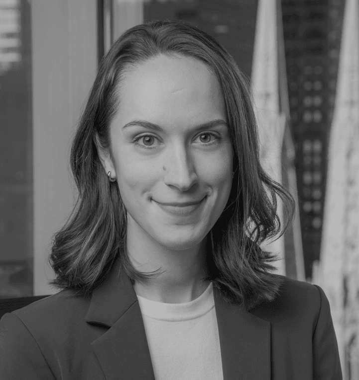 Black and white headshot of a smiling young woman with medium-length dark hair, wearing a blazer.