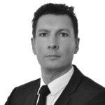 Black and white headshot of a man in a suit and tie looking forward.