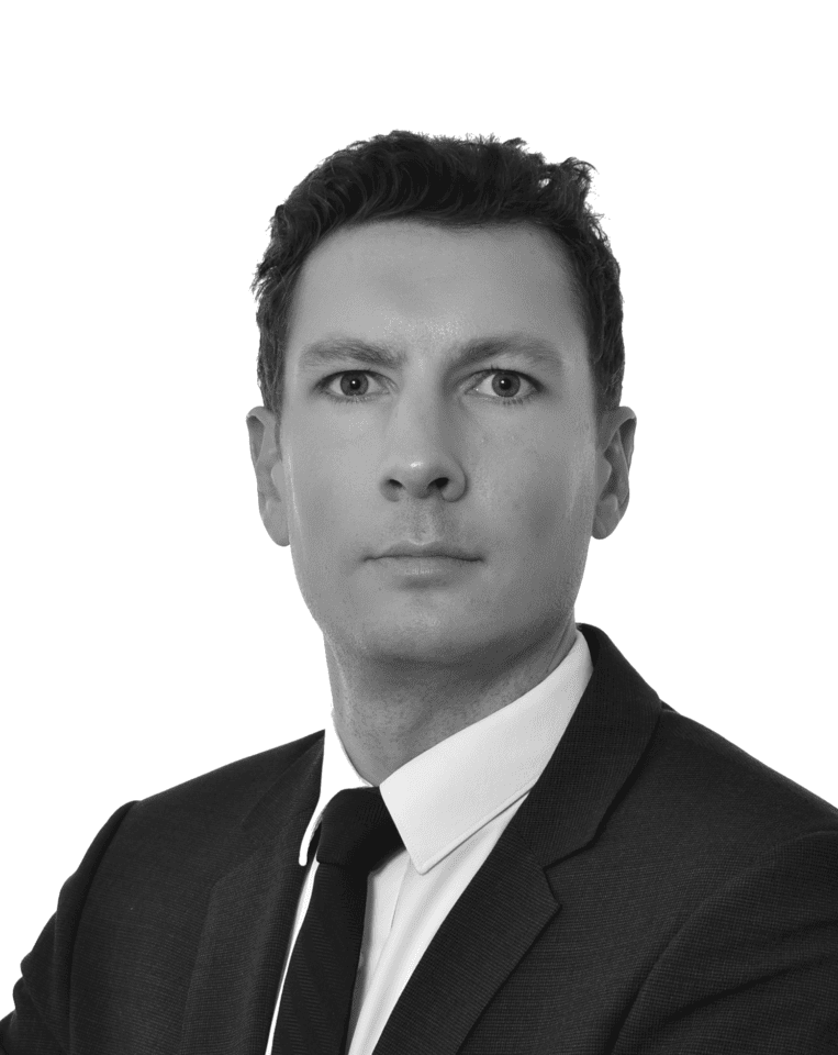 Black and white headshot of a man in a suit and tie looking forward.
