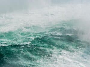 A close-up view of turbulent, green and white water with heavy mist and spray.