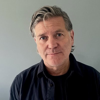 Headshot of a man with grey hair wearing a dark shirt.