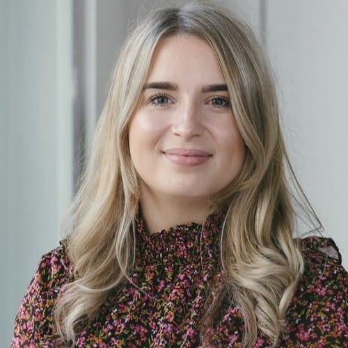 Headshot of a smiling young woman with blonde hair wearing a floral top.