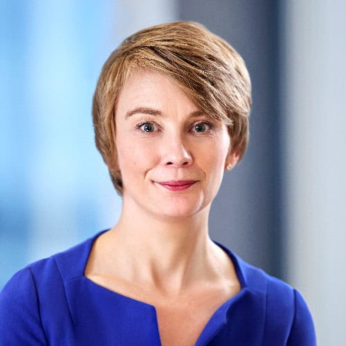 Headshot of a woman with short brown hair, light eyes, and a slight smile, wearing a royal blue top.